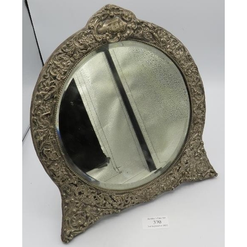 370 - A heavily embossed silver circular table mirror embossed with birds and foliate design, bevelled mir... 