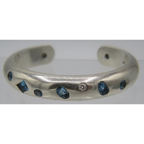 383 - A heavy silver bangle set with two brilliant cut diamonds, approx 0.20cts and seven blue topaz, larg... 