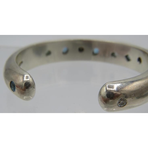 383 - A heavy silver bangle set with two brilliant cut diamonds, approx 0.20cts and seven blue topaz, larg... 