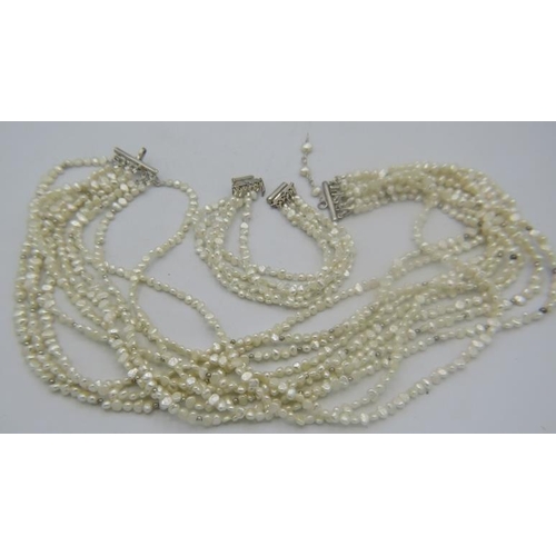 431 - A multi stranded natural Keishi pearl necklace comprising of 10 strands joined together on a white m... 