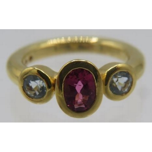 448 - A three stone 18ct yellow gold ring. The centre tourmaline approx 7mm x 4mm and the topaz approx 4mm... 