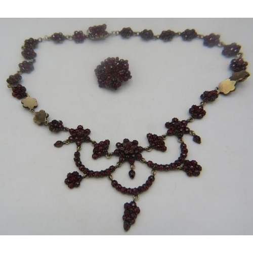 453 - A Czechoslovakian yellow metal garnet necklace made up of clusters of garnets with larger group at t... 