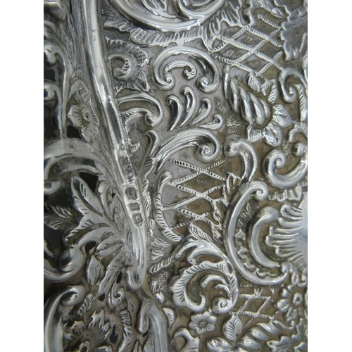 487 - A silver dressing table tray, heavily embossed scrolls & foliate design, Birmingham 1899. Approx 12