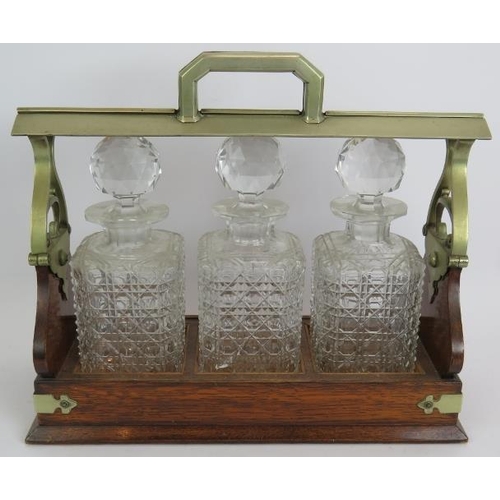 66 - An Edwardian oak 3 decanter tantalus with locking mechanism and nickel mounts. Each decanter hobnail... 