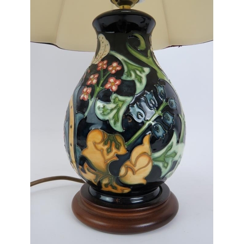 94 - A Moorcroft pottery lamp of balluster form, on a turned wood base. Base height 22cm. Overall height ... 