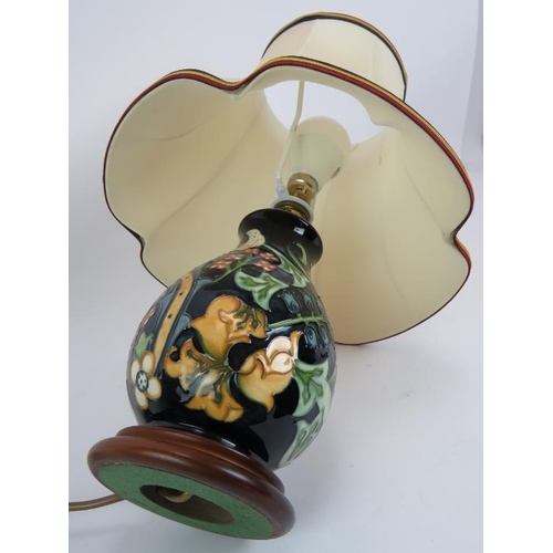 94 - A Moorcroft pottery lamp of balluster form, on a turned wood base. Base height 22cm. Overall height ... 