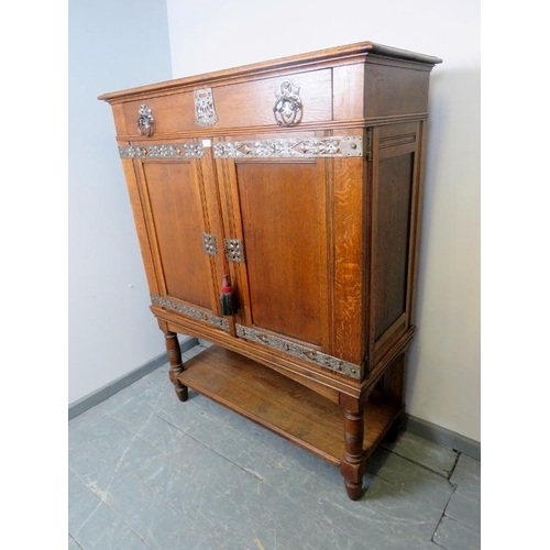 701 - An Arts & Crafts medium oak cabinet featuring ornate pierced steel escutcheons, drop ring handles an... 