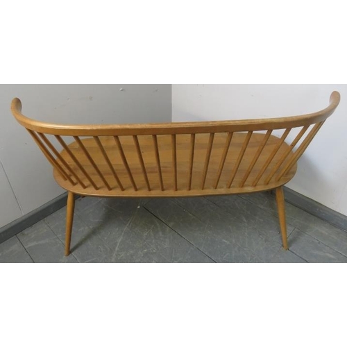 711 - A mid-century blond elm Windsor love seat by Ercol, on canted supports with an ‘H’ stretcher. 
Condi... 