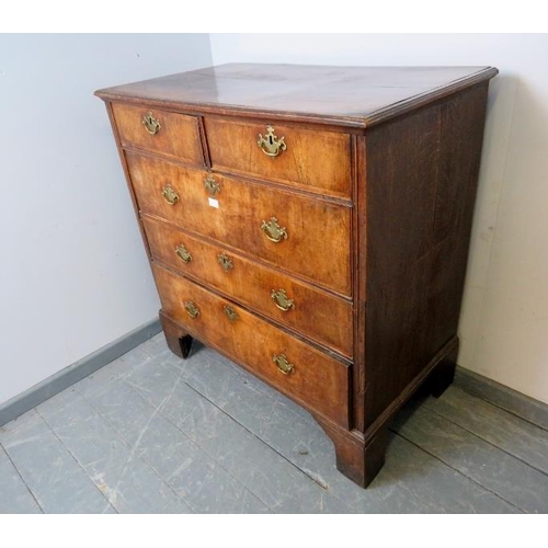 715 - An early 18th century oak and burr walnut chest of two short over three long graduated drawers with ... 