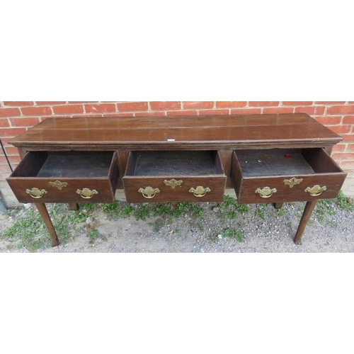 718 - An 18th century oak dresser base of three short drawers, fitted with brass ‘batwing’ handles and loc... 