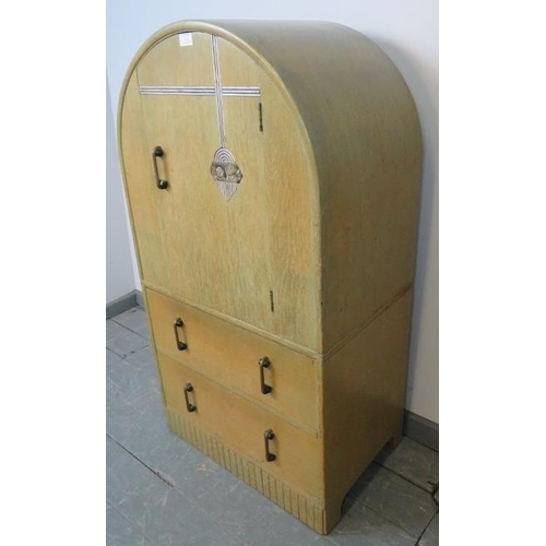 719 - An Art Deco light oak dome topped compactum, the relief carved door opening onto two fitted shelves,... 