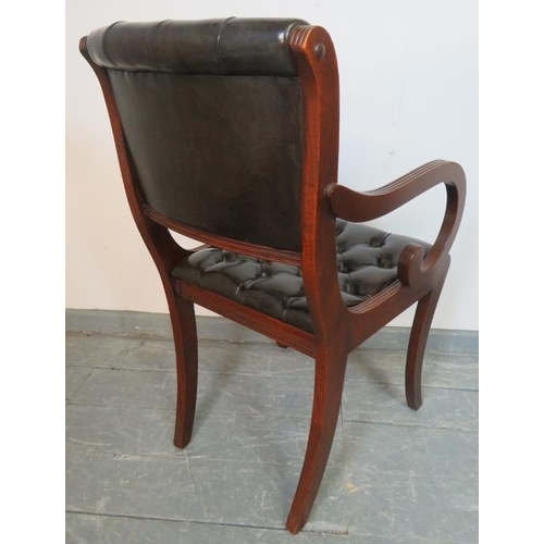 775 - A reproduction mahogany desk chair in the Regency taste, upholstered in chocolate brown buttoned lea... 