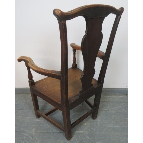 812 - An 18th century elm and oak open sided armchair with shaped back splat and scrolled knuckles, on inn... 