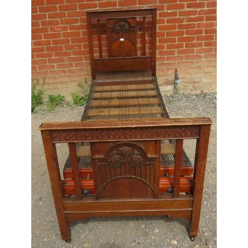 839 - An Edwardian oak single bed with foliate carved head and foot boards and sprung mattress squab. 
Con... 