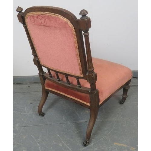 879 - A turn of the century mahogany nursing chair with reeded uprights and finials, upholstered in button... 