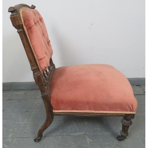 879 - A turn of the century mahogany nursing chair with reeded uprights and finials, upholstered in button... 