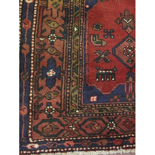 903 - A Persian Zanjan rug, decorated with traditional motifs on a deep red ground within multi-borders, a... 