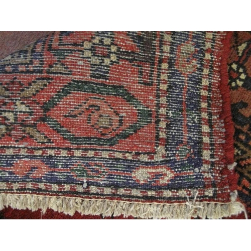 903 - A Persian Zanjan rug, decorated with traditional motifs on a deep red ground within multi-borders, a... 