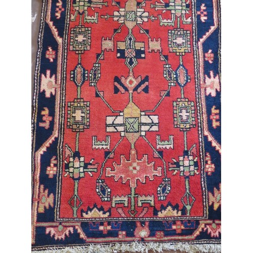 924 - A Persian runner, 20th century, decorated with stylised motifs on a red ground between a stylised bl... 