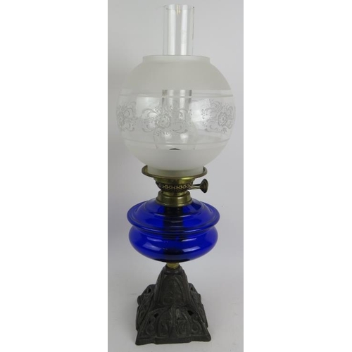 244 - A turn of the century cast iron based oil lamp with Bristol blue reservoir and etched glass shade. O... 