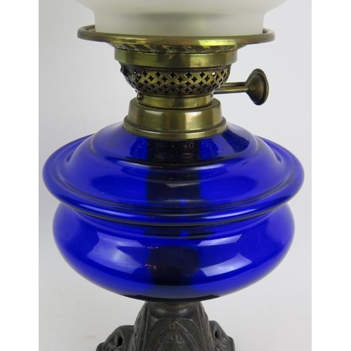 244 - A turn of the century cast iron based oil lamp with Bristol blue reservoir and etched glass shade. O... 