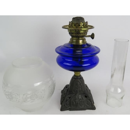 244 - A turn of the century cast iron based oil lamp with Bristol blue reservoir and etched glass shade. O... 