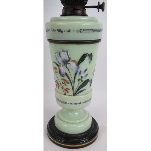 246 - An antique painted glass oil lamp hand decorated with flowers on a ceramic base and with green glass... 