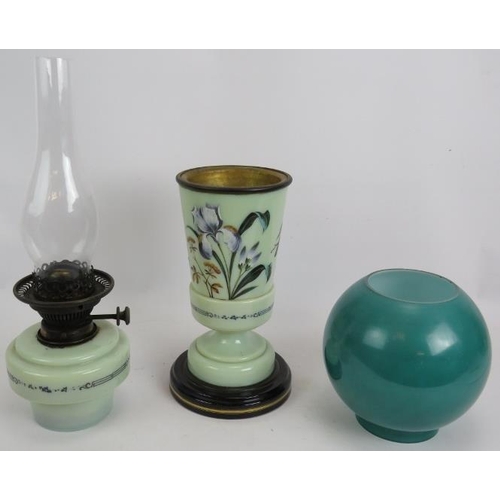 246 - An antique painted glass oil lamp hand decorated with flowers on a ceramic base and with green glass... 