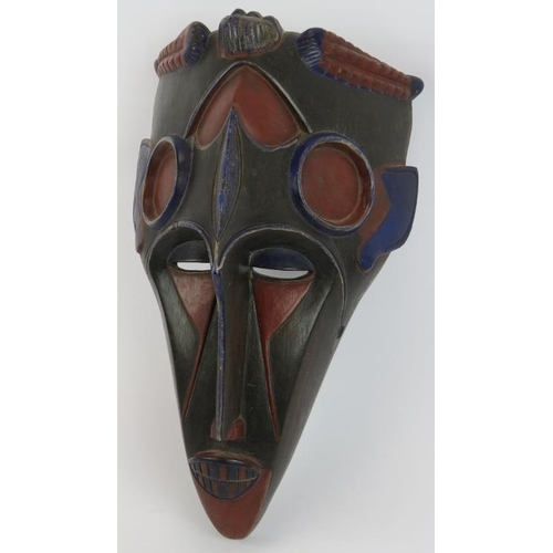 34 - A carved wood West African tribal mask decorated in blue and red polychrome colours. Height 42cm.
Co... 