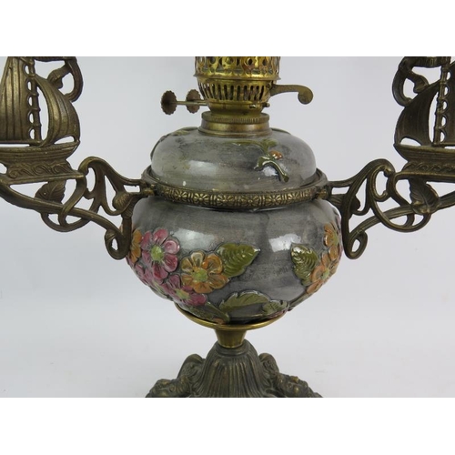 40 - A highly decorative oil lamp with relief moulded pottery reservoir cast brass stand and opaline glas... 