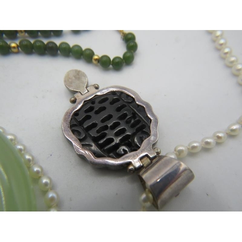 457 - A Chinese black jade split pearl and silver pendant on a natural pearl necklace. Boxed. Two jade ban... 