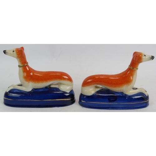 66 - A pair of Staffordshire pottery pen holders in the form of recumbent greyhounds. Height 14cm. Length... 