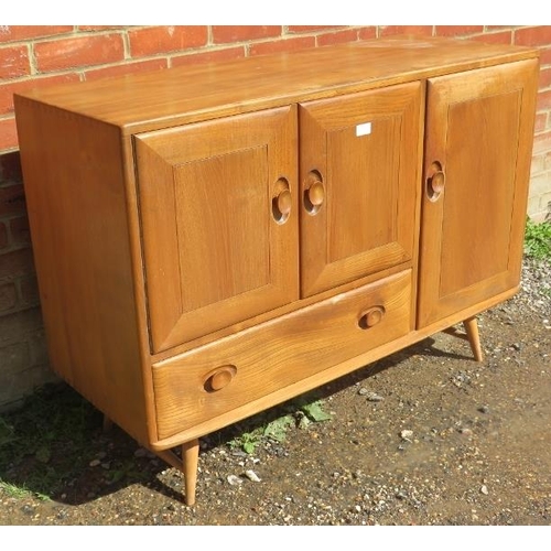 712 - A mid-century elm and beech sideboard by Ercol, housing two cupboards, both with loose shelves, and ... 