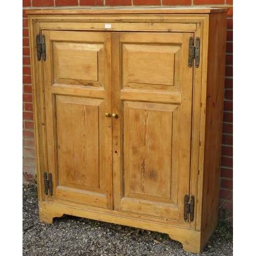 726 - An antique stripped pine pantry cupboard, the doors with fielded panels and cast-iron hinges, openin... 