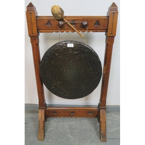 741 - A 19th century Gothic Revival bronze dinner gong, suspended in an oak frame featuring trefoil carved... 