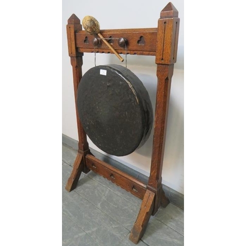 741 - A 19th century Gothic Revival bronze dinner gong, suspended in an oak frame featuring trefoil carved... 