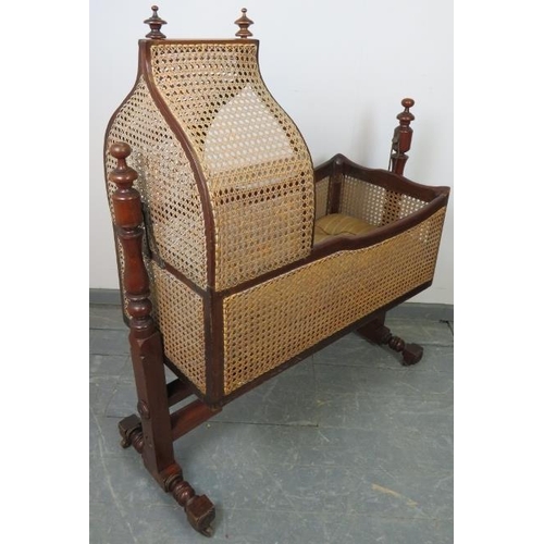 764 - A turn of the century mahogany rocking crib with turned finials and bergère sides and canopy, on a b... 