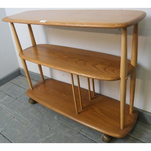 767 - A mid-century blonde elm ‘baby giraffe’ Windsor book trolley by Ercol (model 361) of three shelves, ... 