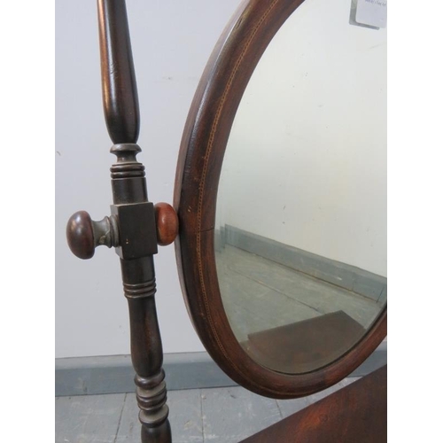 785 - A Georgian flame mahogany oval bevelled swing vanity mirror, with parquetry inlay and turned upright... 