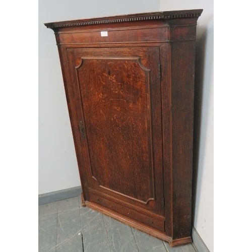 791 - A Georgian oak hanging corner cupboard, with dentil cornice, three fitted shelves and single drawer ... 