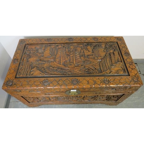 803 - A vintage Chinese export camphorwood trunk, with ornate relief carving depicting sailing junks and b... 