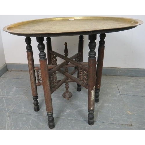 814 - A vintage Benares table, the brass tray top hand tooled with Egyptian motifs, on folding oak support... 