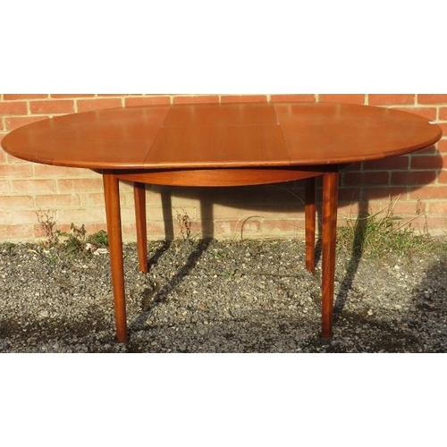 817 - A mid-century teak circular dining table by McIntosh, with central butterfly leaf extension, on tape... 