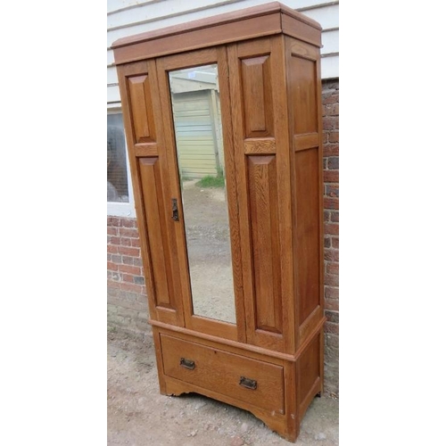 826 - An Edwardian light oak single wardrobe, with bevelled mirror door and fielded front panels, with one... 