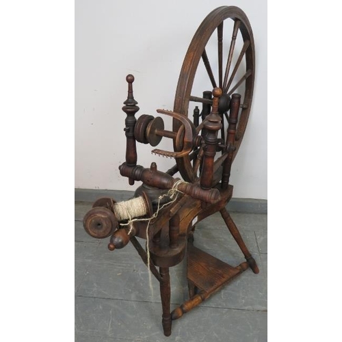 855 - A 19th century oak and mahogany pedal driven flax spinning wheel with turned finials. Includes two a... 