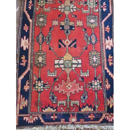 906 - A Persian runner, 20th century, decorated with stylised motifs on a red ground between a stylised bl... 