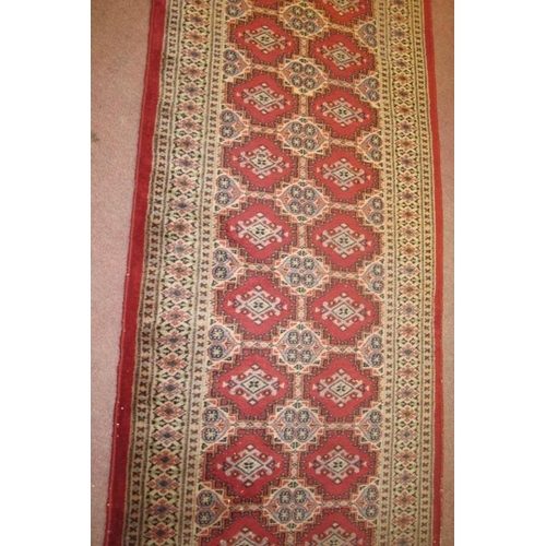 924 - A Persian runner, repeat central pattern on red ground, 545cm x 83cm, some wear/fading.