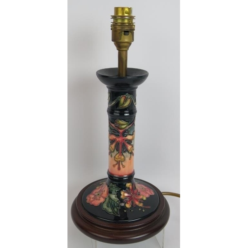 114 - A Moorcroft pottery candlestick lamp base decorated with floral motifs mounted on a turned wood base... 