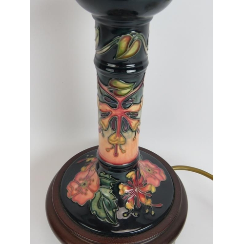 114 - A Moorcroft pottery candlestick lamp base decorated with floral motifs mounted on a turned wood base... 