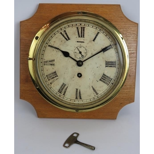 127 - An early 20th century brass cased ships clock on oak mount. Key present. Dial 20cm diameter.
Conditi... 